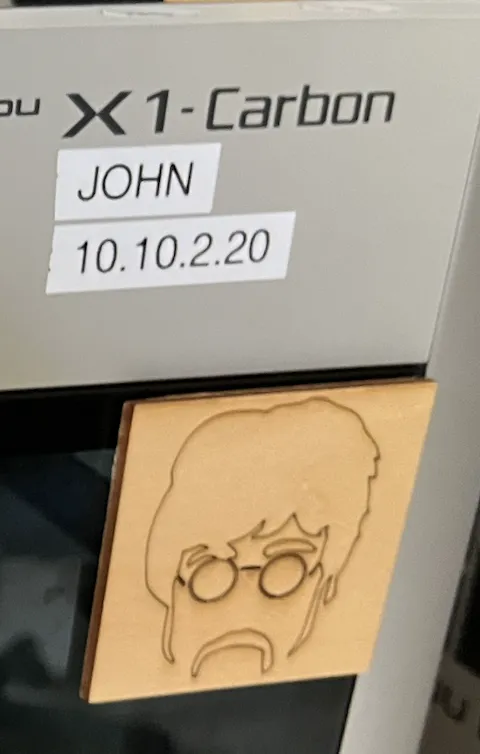 A Bambu Lab X1 Carbon with a printed label reading JOHN on the front of the case