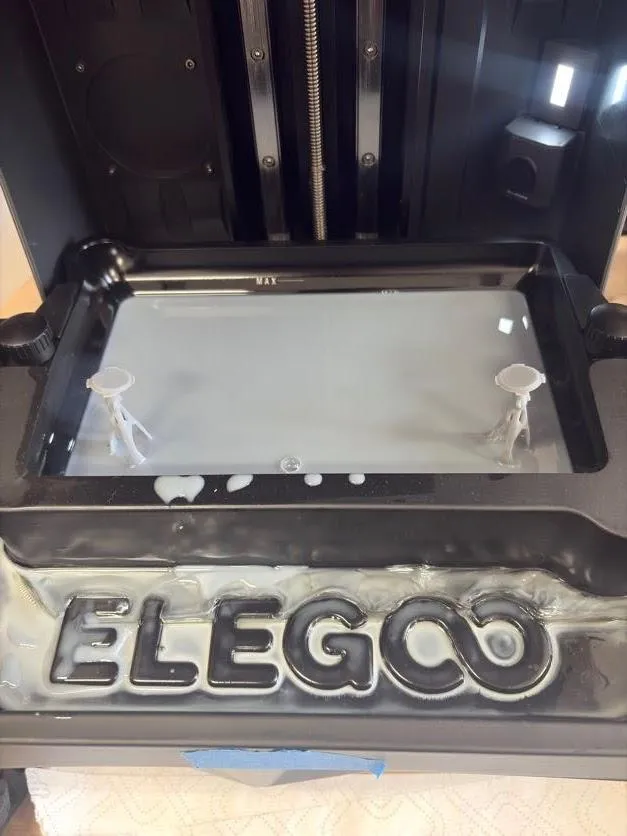 Two printed stems standing at the front corners of the resin tank