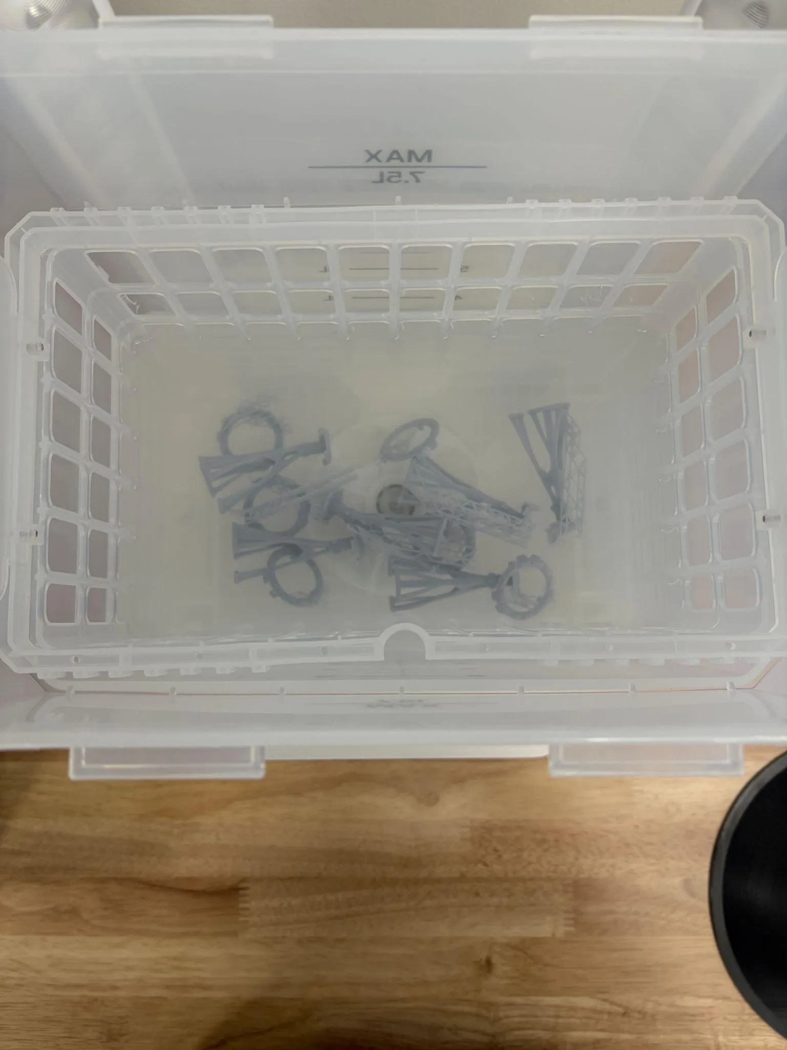 Parts sitting in the cleaning basket inside the bucket of IPA