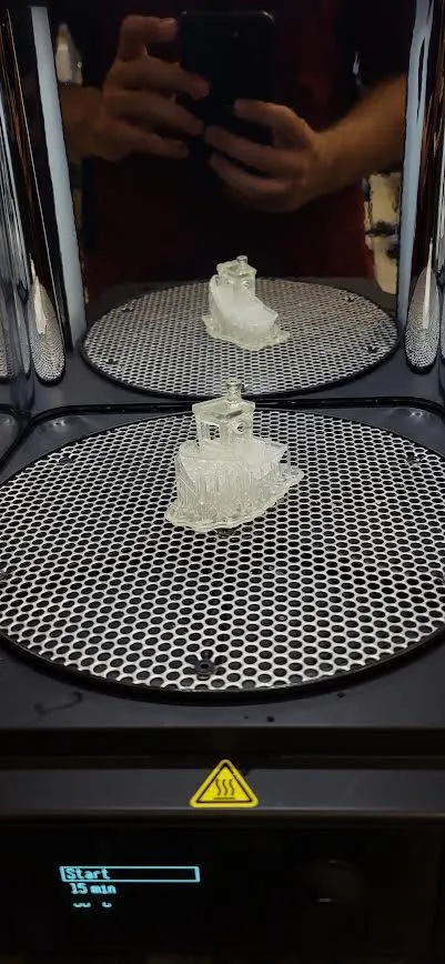 Two clear resin boat prints standing on the Form Cure's perforated turntable, with the display reading Start and 15 min