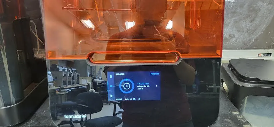 Looking down through the Form 3 cover at the build platform lowered into the resin tank mid-print