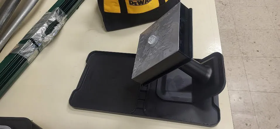 A build platform with a finished print seated at an angle on its black jig, on the finishing tray