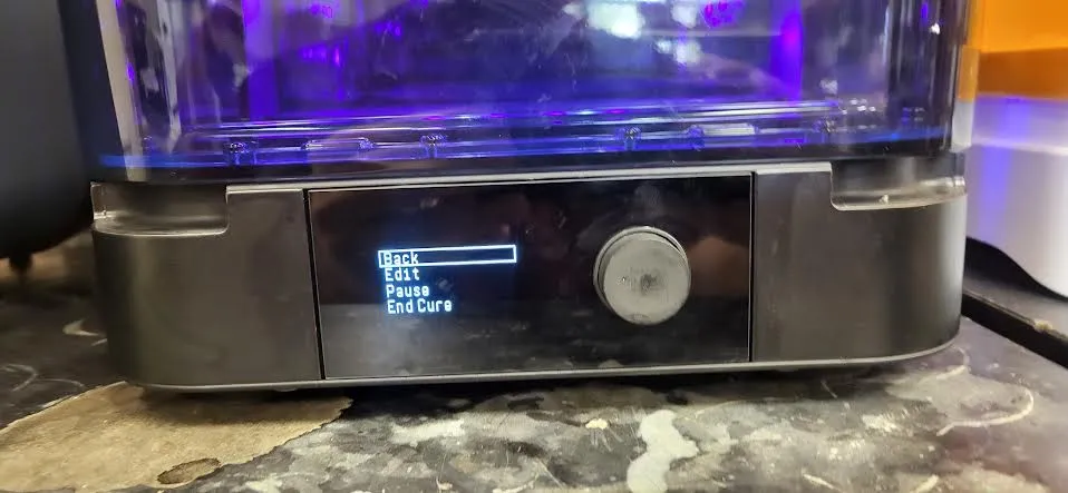 The Form Cure display showing the running-cycle menu — Back, Edit, Pause, End Cure — with the chamber glowing violet above it