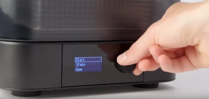 A hand pushing the Form Wash's knob, with the display showing Start, 10 min and Open