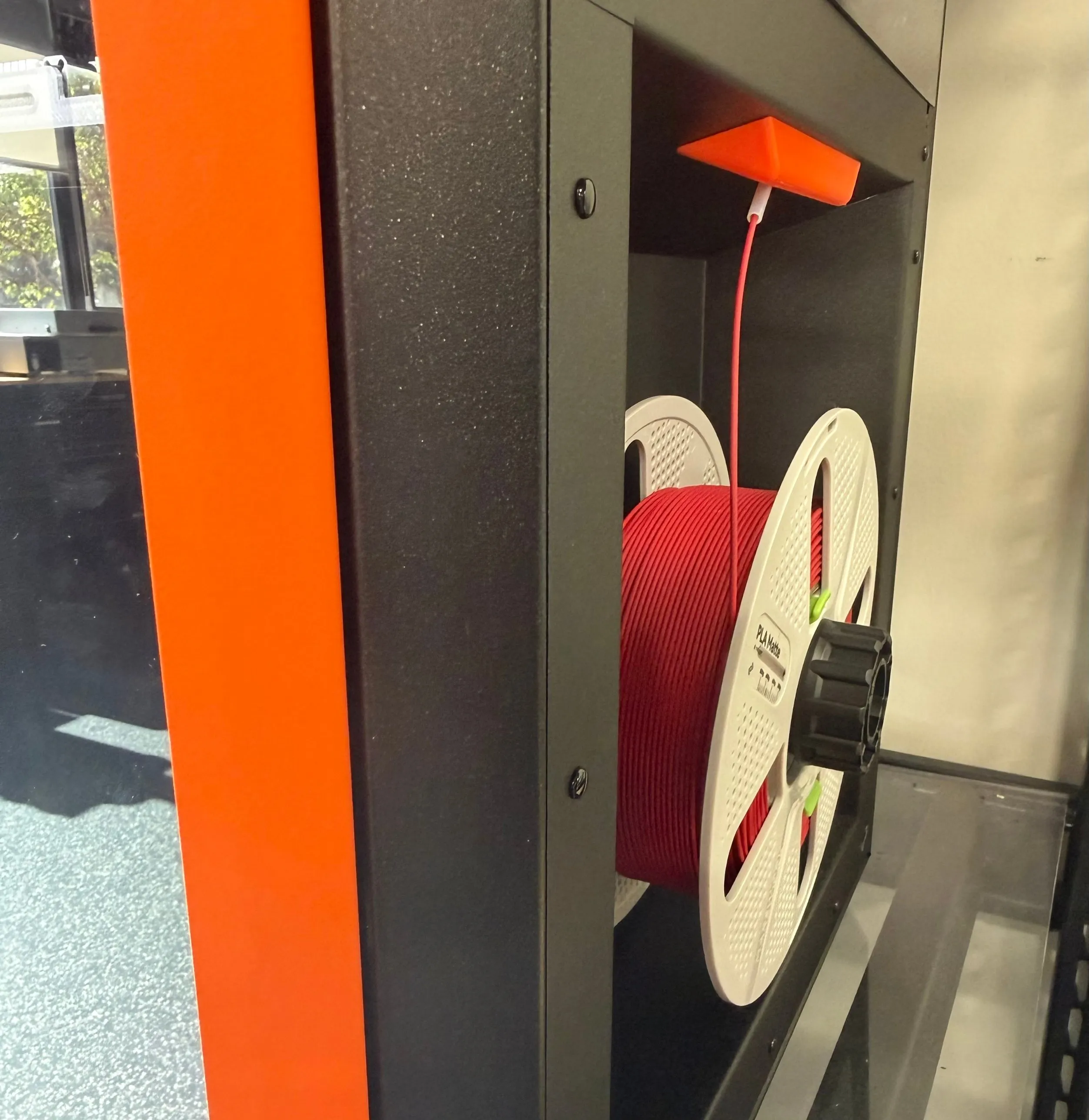 A fully loaded spool with the filament running from the spool up through the PTFE tube into the printer
