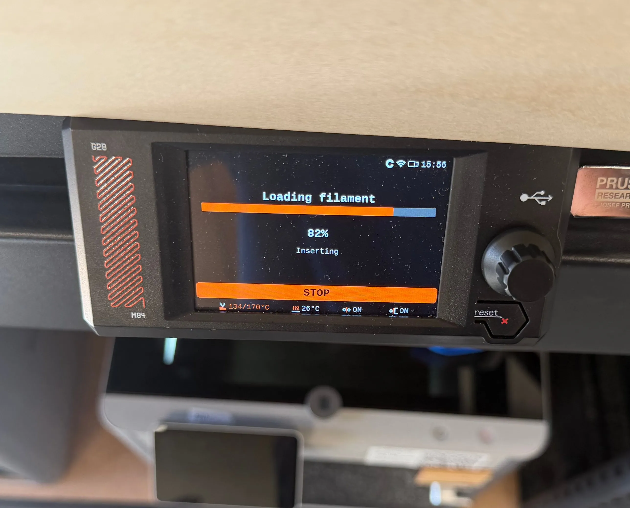 The printer display showing the Loading filament screen at 82% with the status Inserting